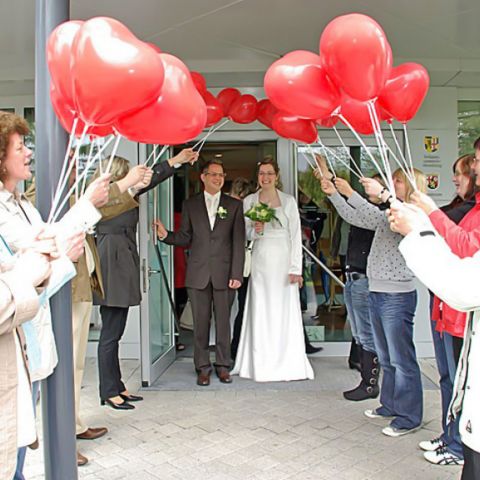 Das Brautpaar kommt aus dem Standesamt und die Freunde bilden ein Spalier mit Herzballons.