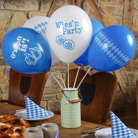 Oktoberfest-Deko-Luftballonns mit Haltestäben in einer Kanne auf einm Tisch, geschmückt für's Oktoberfest.