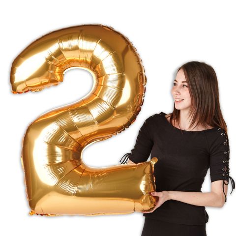 Großer goldener Folienballon Zahl "2" im Größenverhältnis zu einer Person zu sehen.
